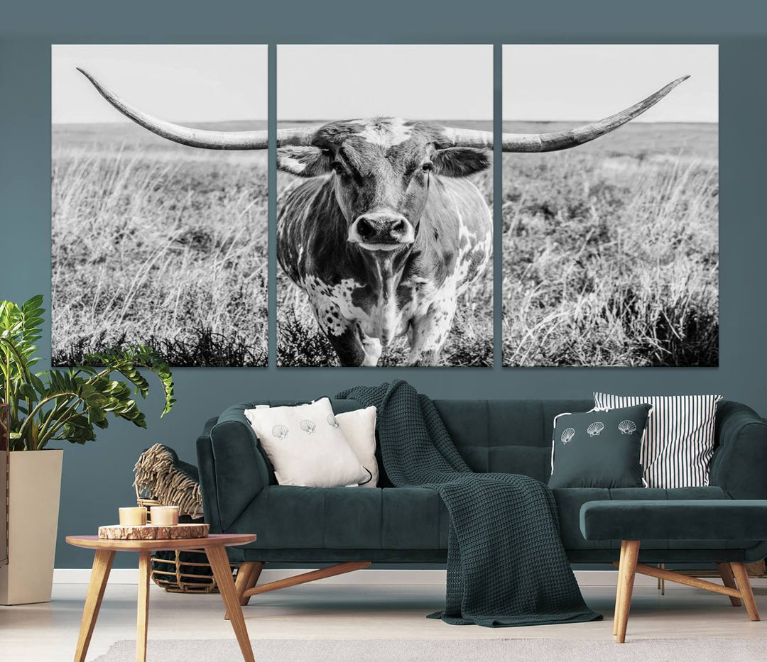 The Texas Cow Longhorn Wall Art Canvas Print is a black and white triptych depicting a cow in a field. It is crafted with museum-quality canvas and features a UV-protective coating.