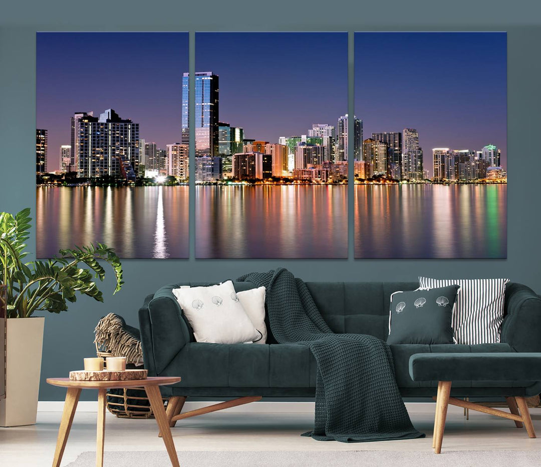 The Miami Skyline Canvas Wall Art Print showcases a vibrant night cityscape and beautifully captures the dazzling colorful lights reflecting on the water. This ready-to-hang triptych adorns the wall, creating a stunning visual centerpiece.