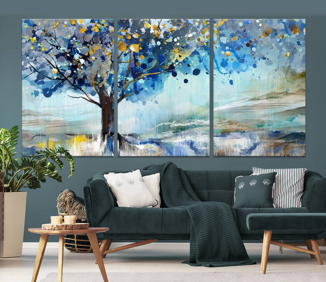 A modern living room features a three-panel Watercolor Style Abstract Tree Printing Wall Art Canvas in vibrant blue and yellow, crafted on museum-quality material.