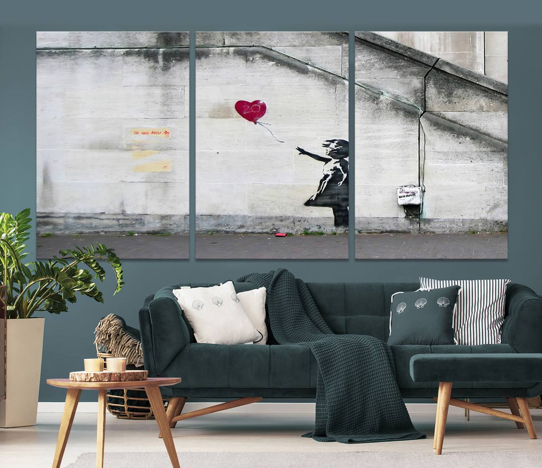 The "Girl with a Balloon Banksy Street Graffiti Art Canvas Print" is a gallery-quality wall art piece that features an image of a girl releasing a heart-shaped balloon. Handmade in the USA, this canvas artwork brings charm and emotion to any room.