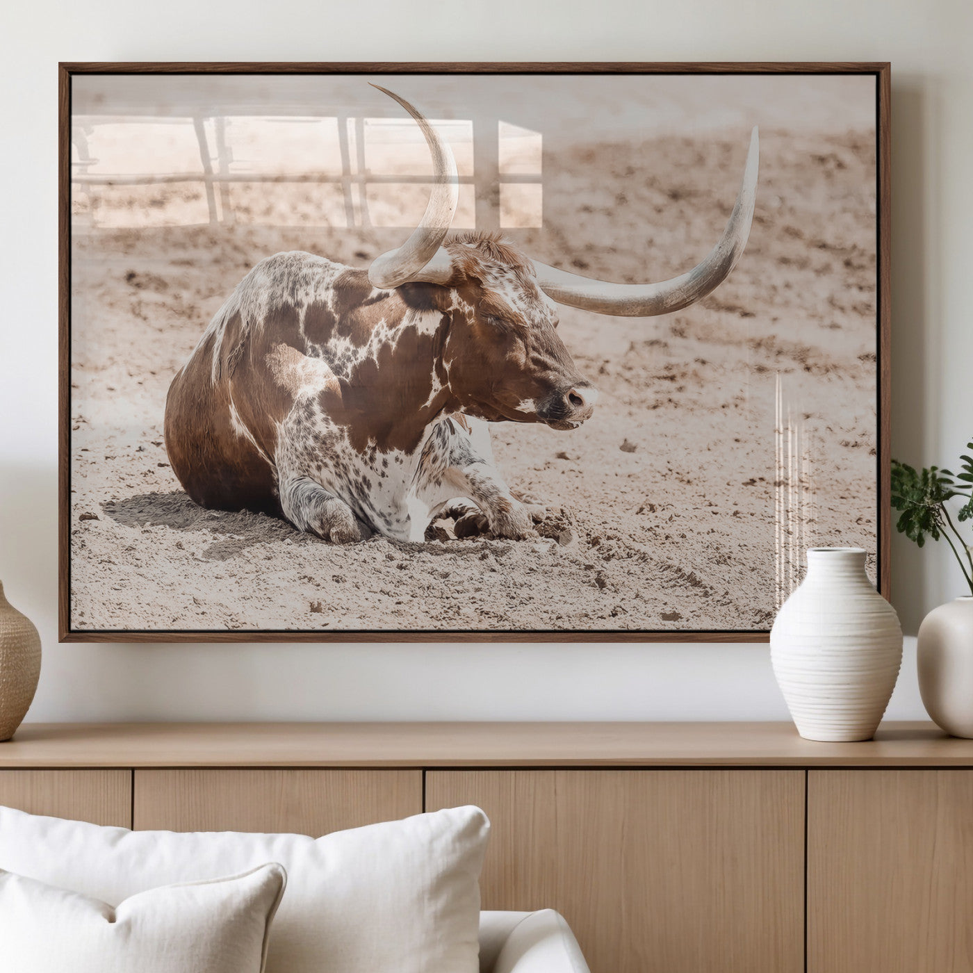 Texas Longhorn bull resting on dusty ground with warm tones, ideal for rustic western or farmhouse-themed wall decor.