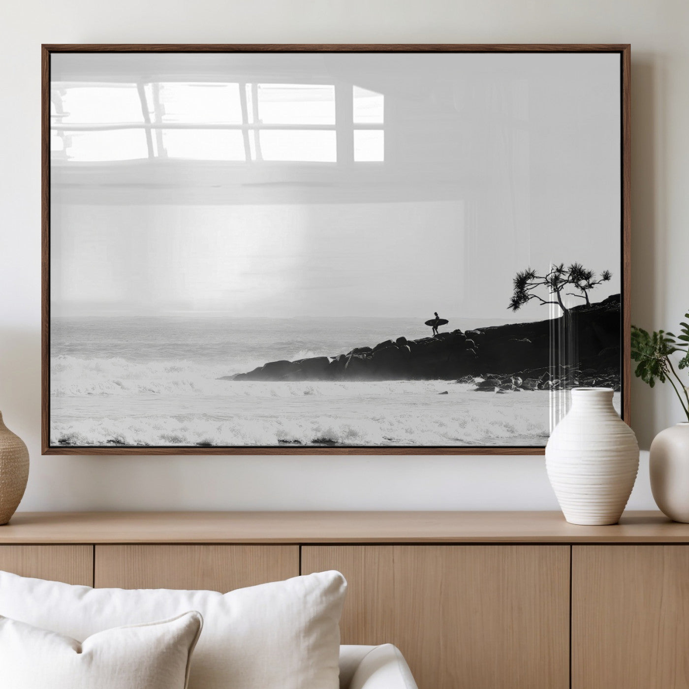 Black and white photo of a surfer standing on rocky cliffs, gazing at the waves, embodying the spirit of adventure and solitude.