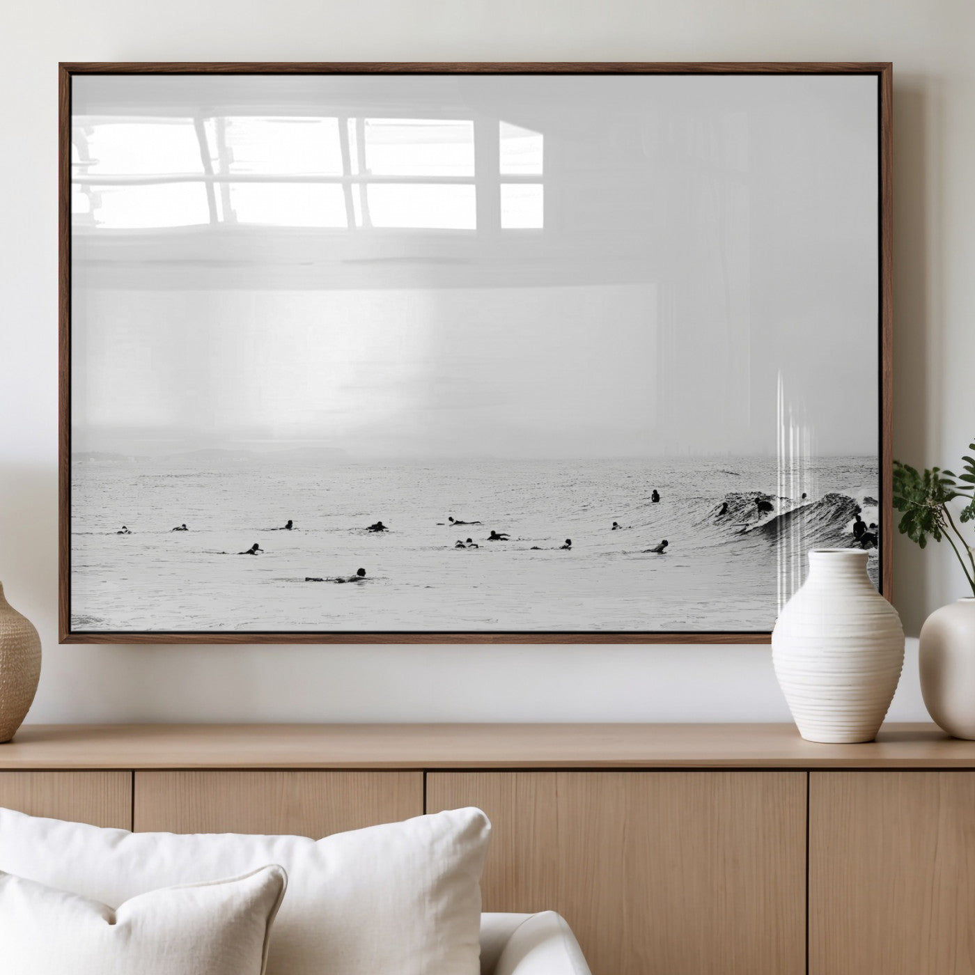 A group of surfers floating in the ocean, waiting for waves under a vast, moody sky, captured in black and white.