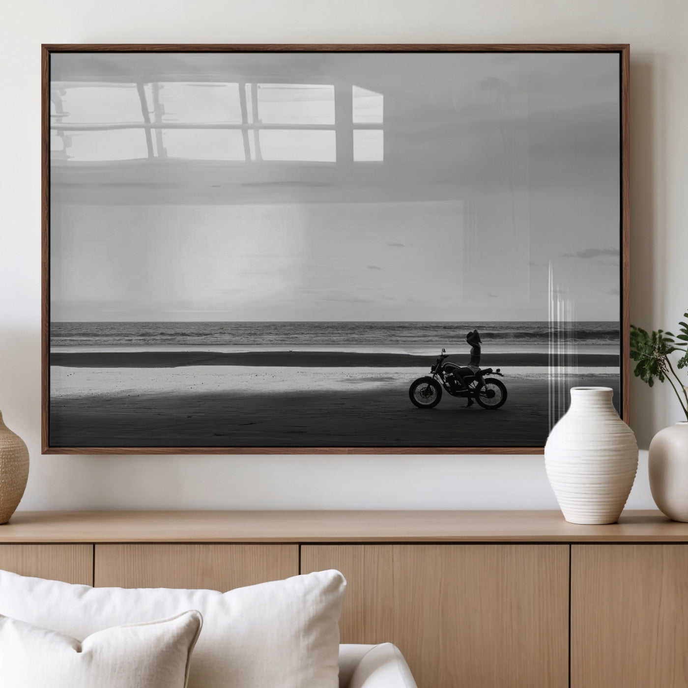 A motorcyclist on a vast beach, gazing at the ocean, capturing a moody and tranquil coastal adventure in black and white.