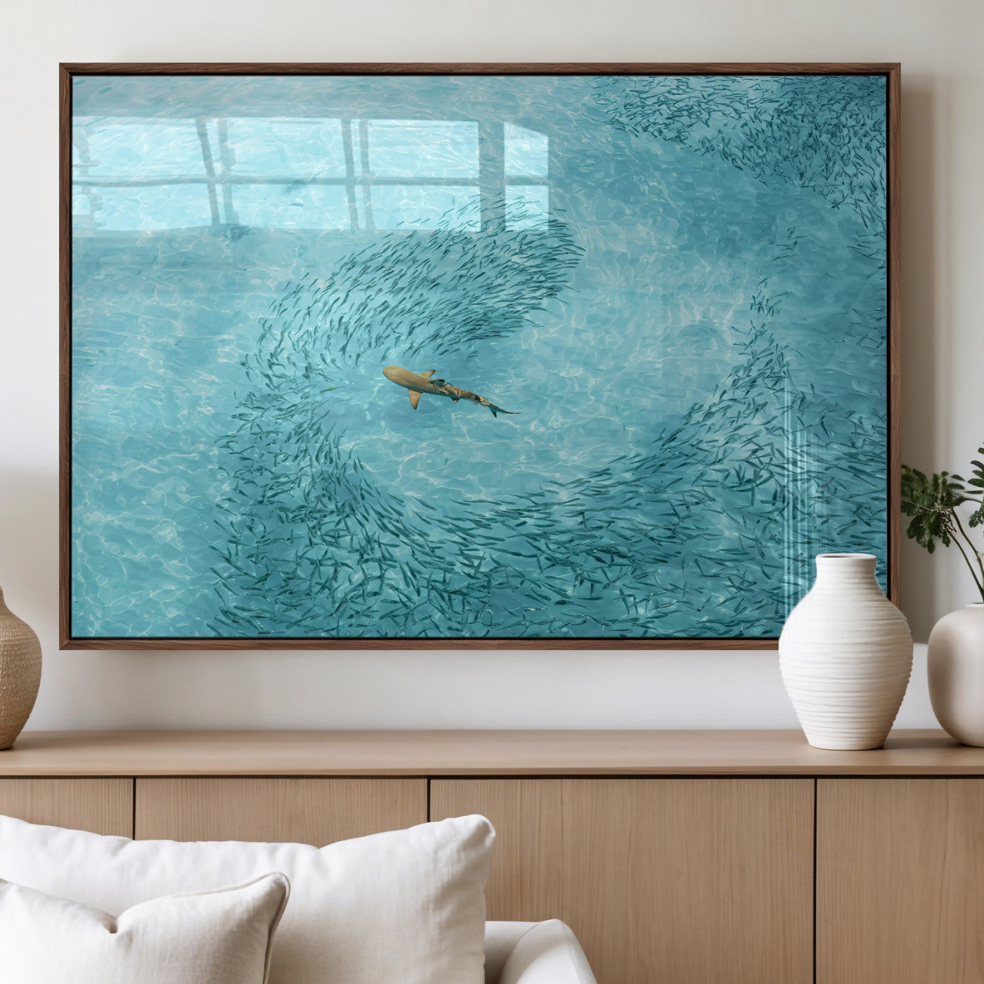 Aerial view of a shark swimming through a swirl of fish in clear turquoise waters, perfect for calm coastal or beach house decor.