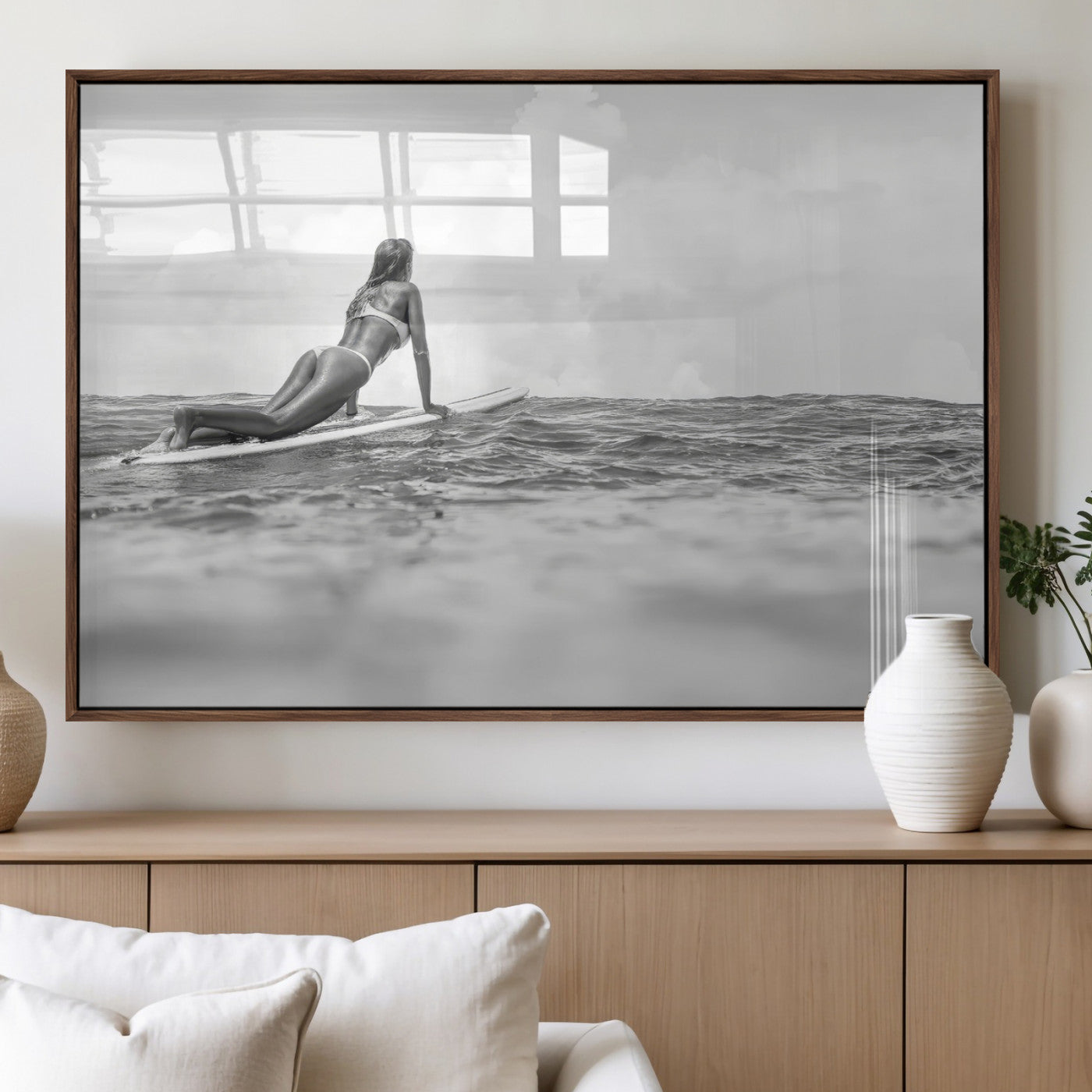 A black and white ocean scene featuring a surfer girl waiting on her board, gazing at the horizon, capturing a tranquil and adventurous coastal moment.