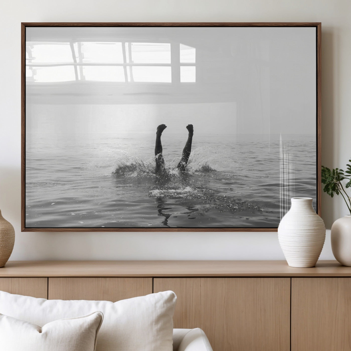A black and white minimalist water scene capturing a playful splash as a swimmer dives upside down, creating a carefree and artistic aquatic aesthetic.
