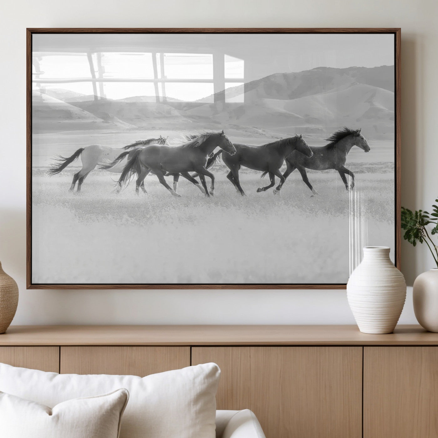 A black and white image of wild horses running freely across an open grassland, capturing the power and beauty of untamed nature in a rustic western setting.