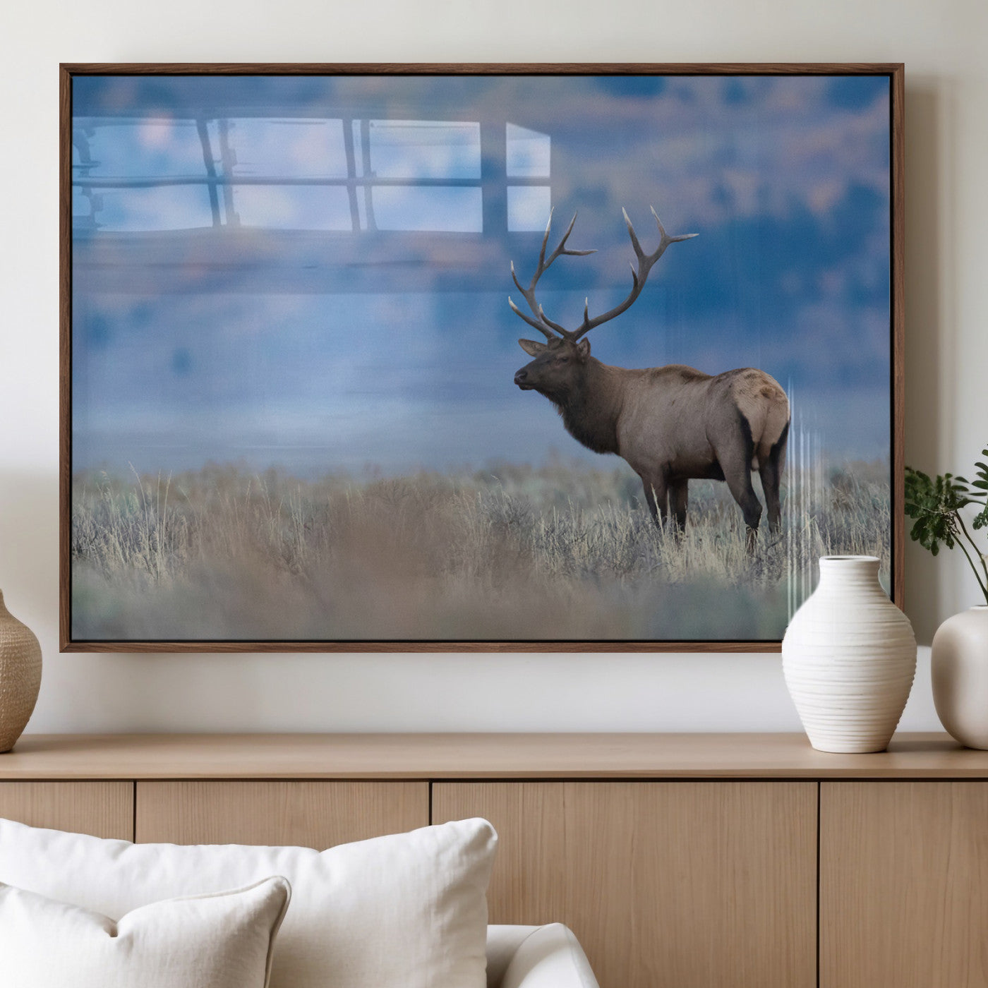 Elk with large antlers standing in open field, mountains blurred in background, perfect for rustic cabin or lodge-style decor.