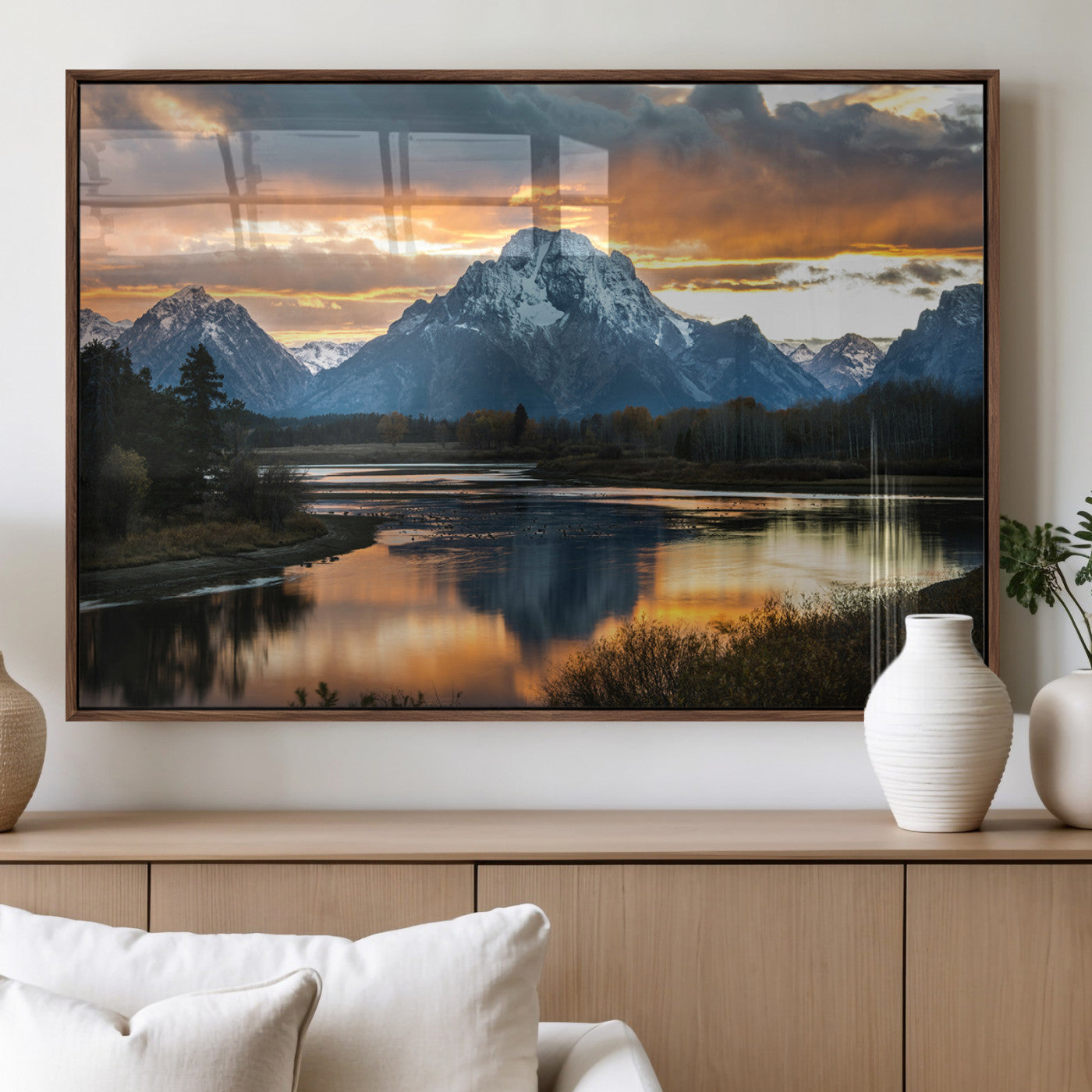 Snow-capped mountains reflecting in a calm lake at sunset, with a dramatic golden sky creating a breathtaking wilderness scene.