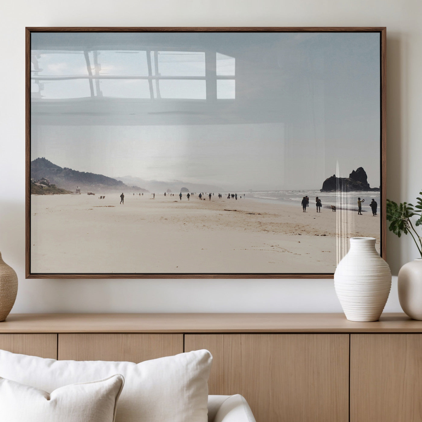 A serene beach with soft sand, misty mountains, and scattered people walking along the shoreline, creating a peaceful coastal landscape.