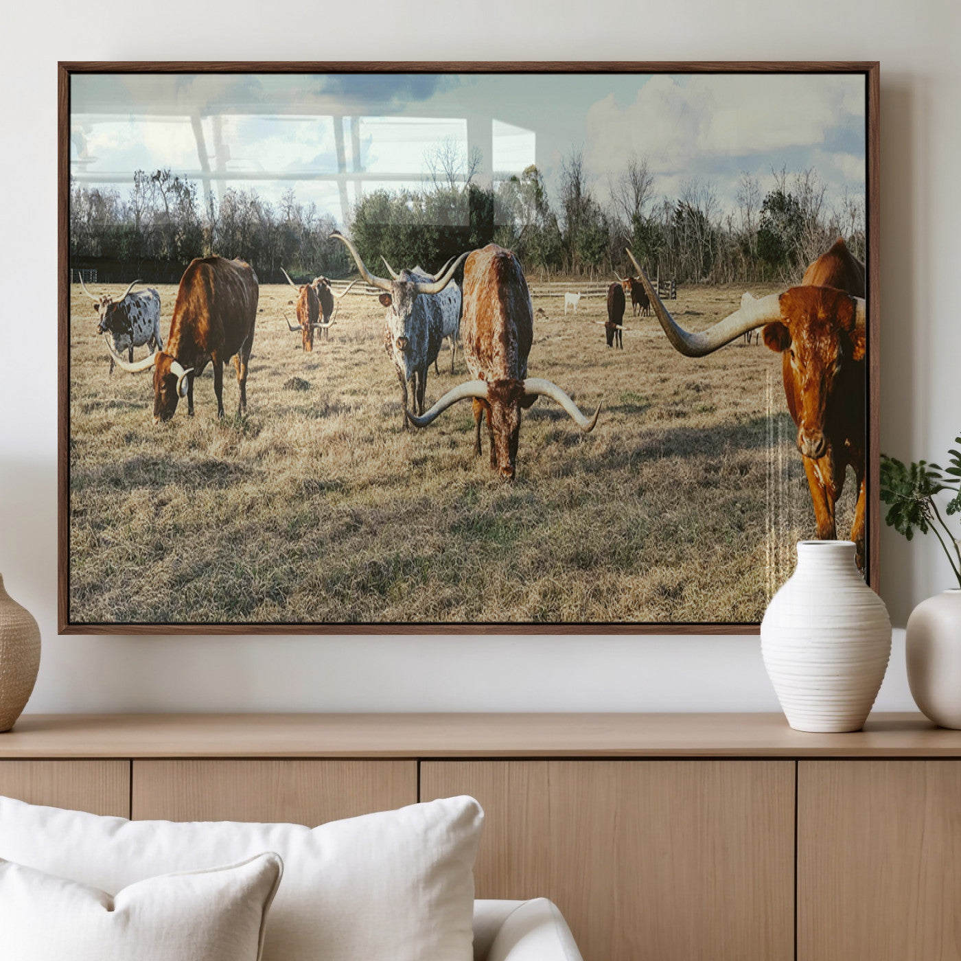 A herd of Texas Longhorn cattle grazing in an open field under a partly cloudy sky, capturing a rustic and Western ranch aesthetic.