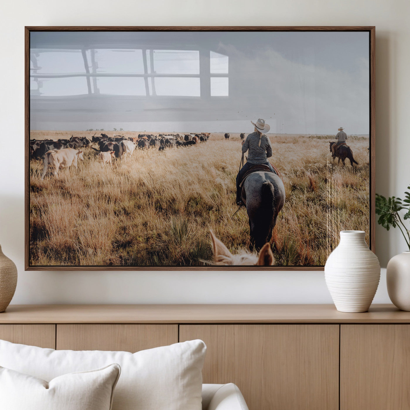 A cowboy and cowgirl on horseback herding cattle through golden grasslands, capturing a rustic and authentic Western ranch lifestyle.