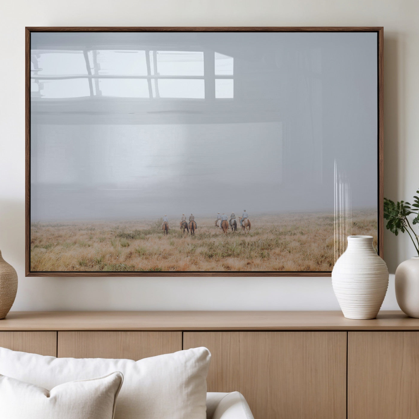 A group of horseback riders moving through a fog-shrouded field, evoking a calm Western scene with golden grasses and soft horizons.