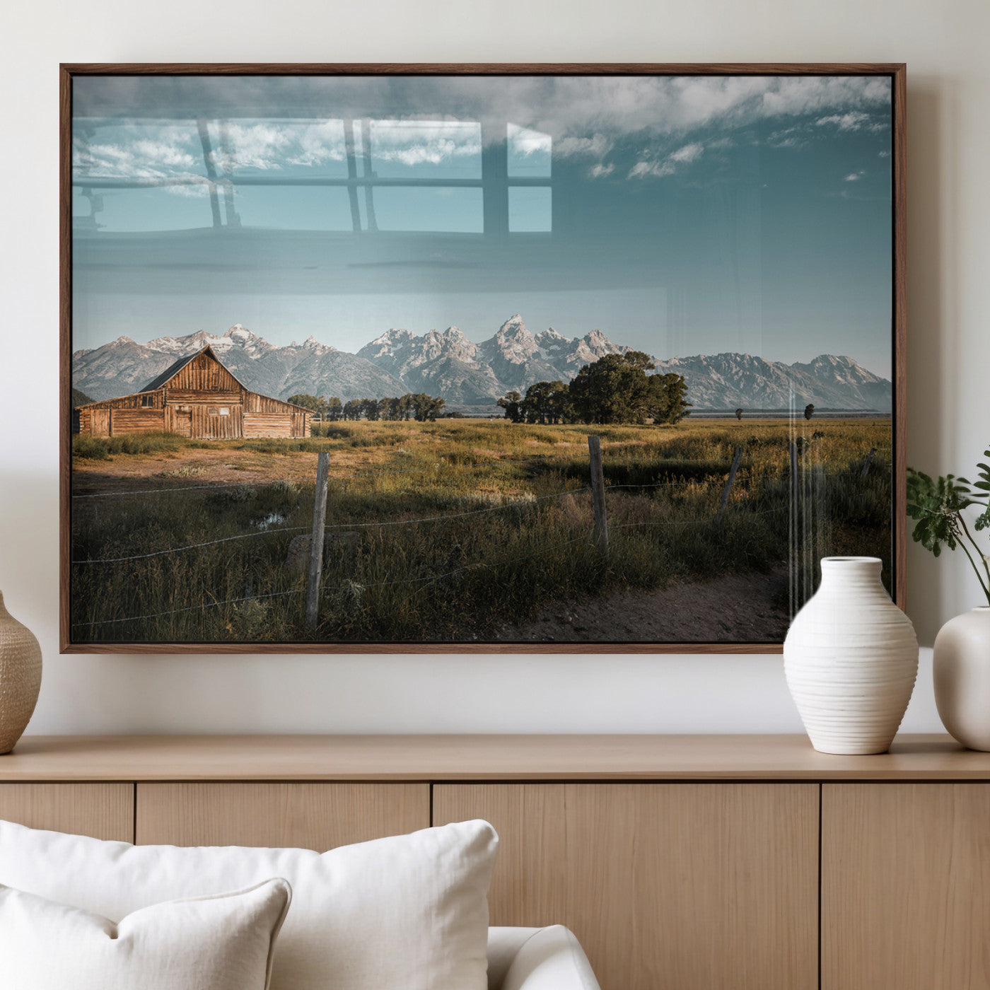A rustic farmhouse with a wooden barn set against majestic mountain peaks under a soft blue sky, evoking peaceful countryside charm.