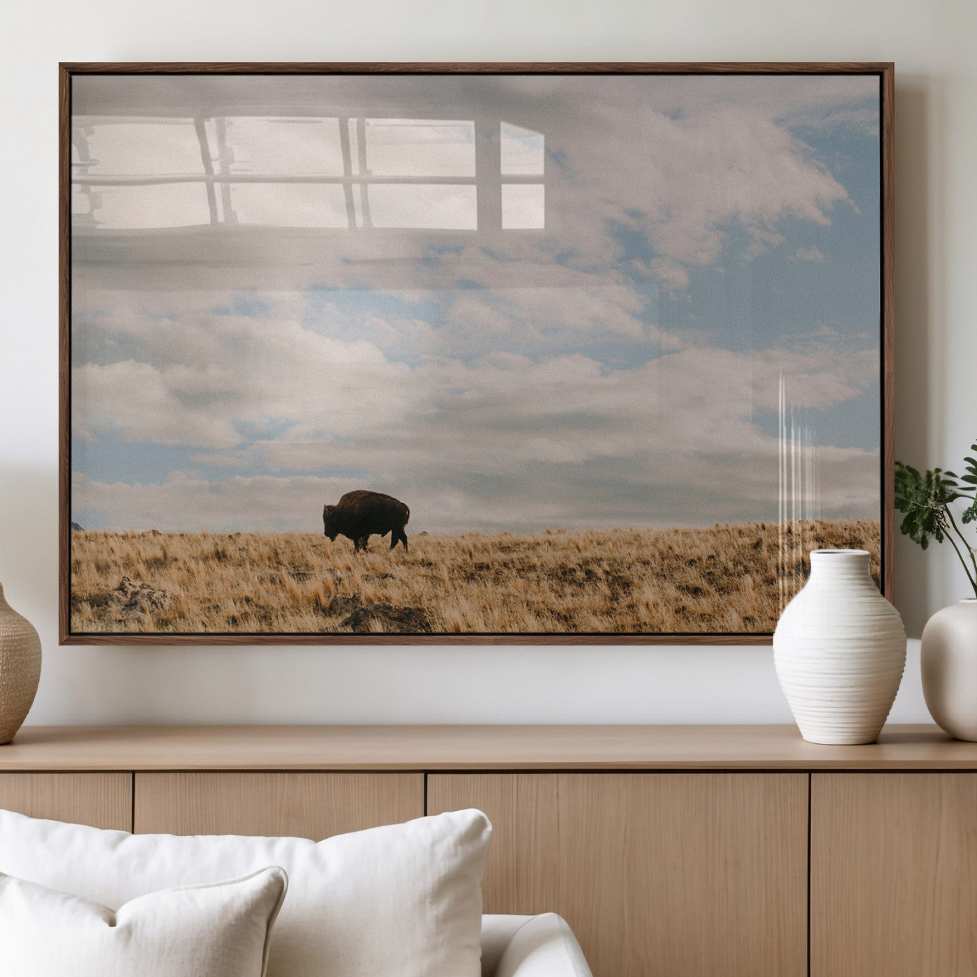 A solitary bison walking across a golden prairie under a vast, cloud-filled sky, evoking a peaceful, rustic western landscape for home decor.