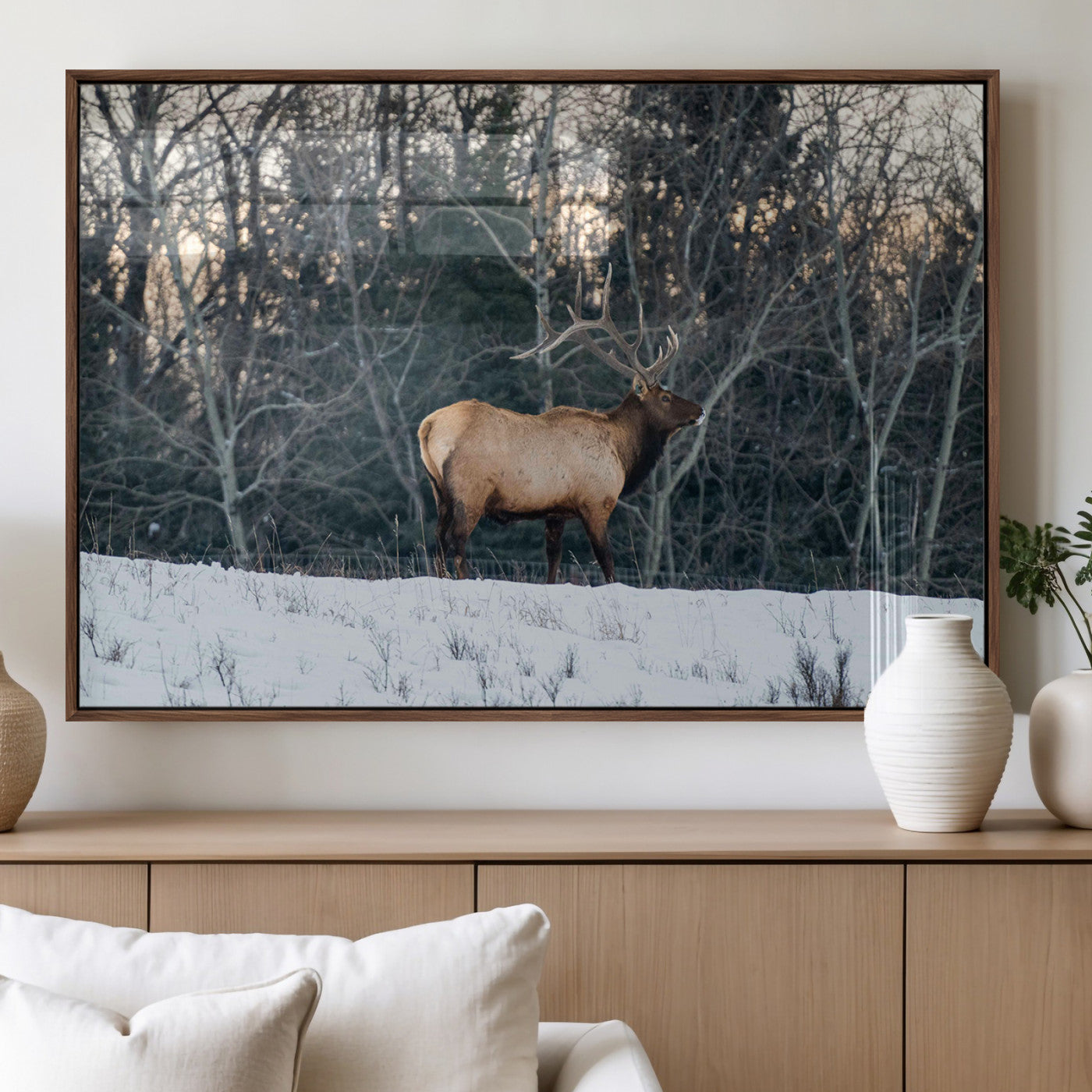 A majestic elk with large antlers standing in a snowy field against a winter forest backdrop, perfect for rustic and wildlife-themed home decor.