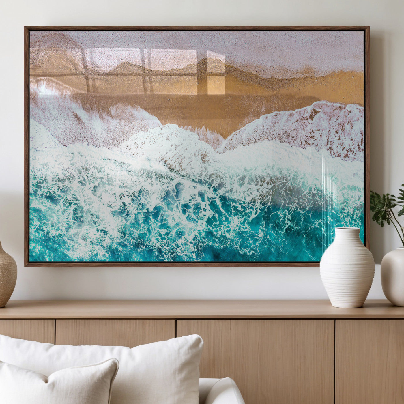 Aerial view of ocean waves crashing onto a sandy beach, with turquoise water and foamy white surf, creating a serene coastal aesthetic for home decor.