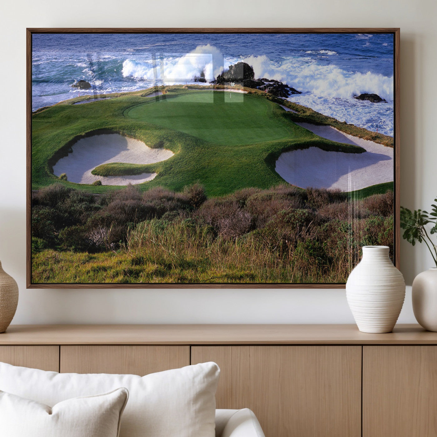 A scenic golf course located by the ocean, featuring a well-manicured green surrounded by sand traps and powerful ocean waves crashing on the shore.