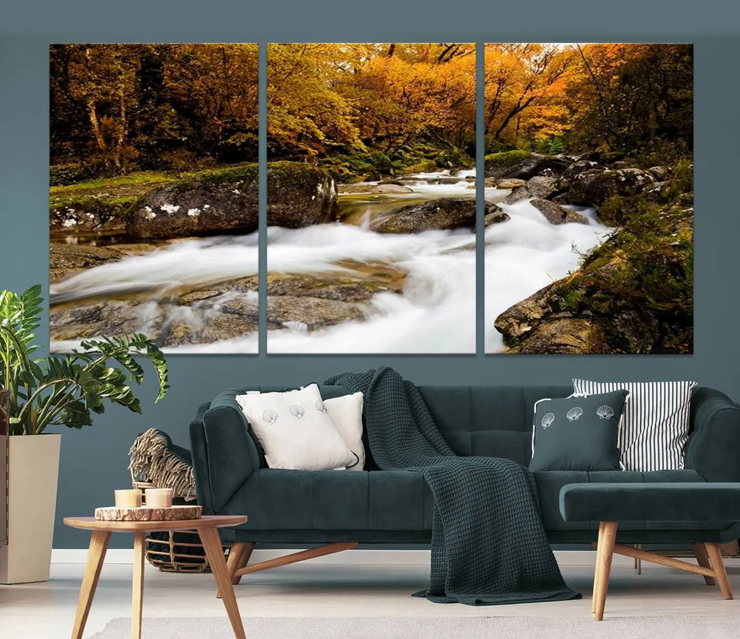 The living room is adorned with the "Wall Art Waterfall Canvas Print River in Forest in Autumn," a triptych on museum-quality canvas showcasing a flowing river surrounded by autumn trees. This ready-to-hang artwork features a UV-protective coating to ensure enduring vibrancy.