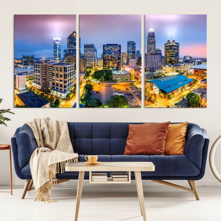 The living room features three large pieces of the *Charlotte City Lights Sunset Purple Skyline Cityscape View Wall Art Canvas Print*. Crafted on gallery-wrapped, museum-quality canvas with UV-protective coating, they grace the wall and add an artistic flair to the space.