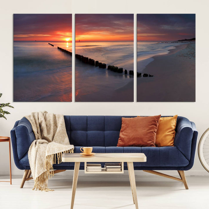 In a modern living room, the Sunset Beach Wall Art Canvas Print is displayed above. This triptych, printed on museum-quality canvas with a UV-protective coating, ensures lasting brilliance. It's ready to hang and brings an elegant touch to your space.