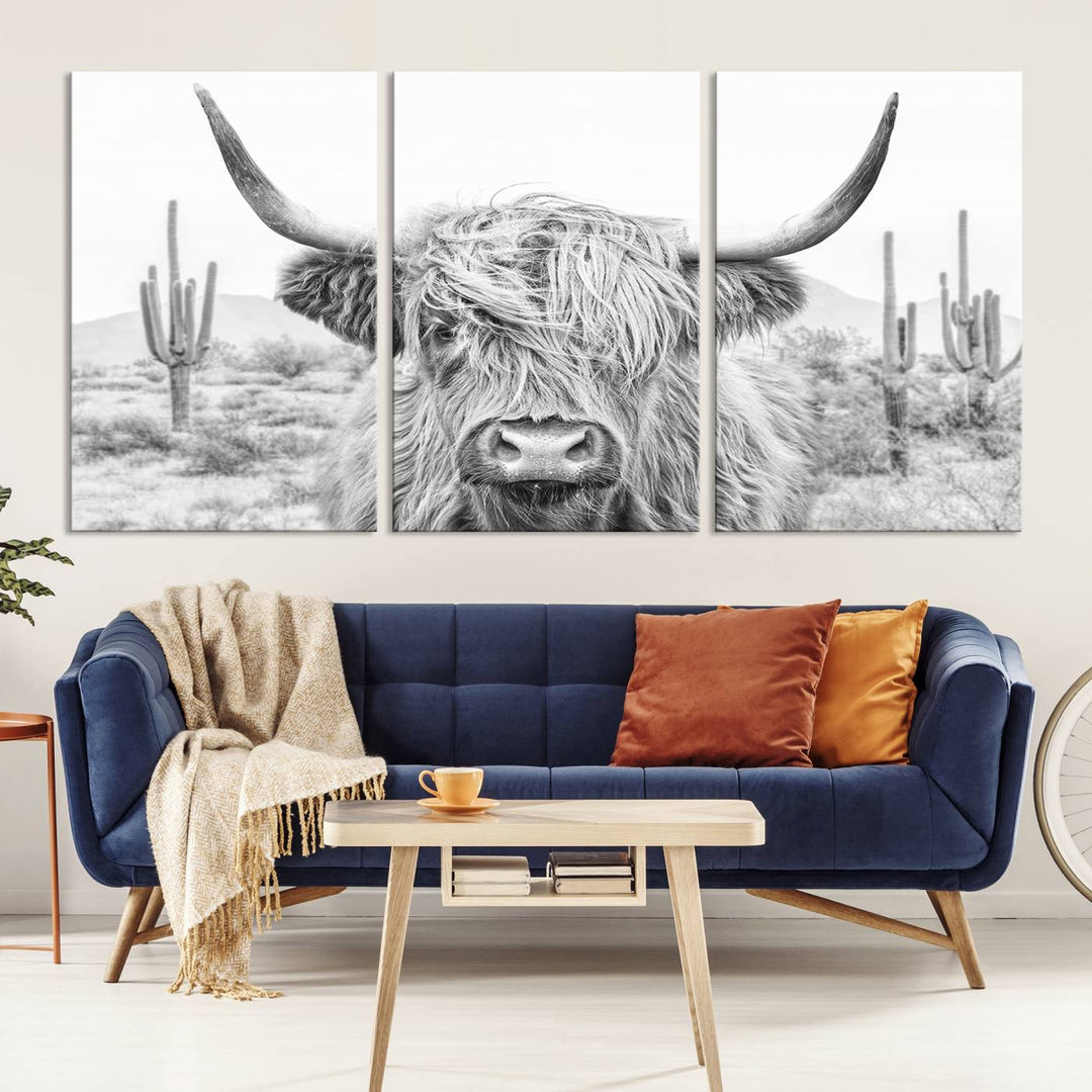 The "Rustic Charm | Cow Longhorn Black White Bighorn Wall Art Canvas Print" is a stunning triptych that showcases a highland cow with long horns set against a desert landscape with cacti in the background. This farmhouse wall art elevates any room into a rustic haven with its gallery-quality canvas.