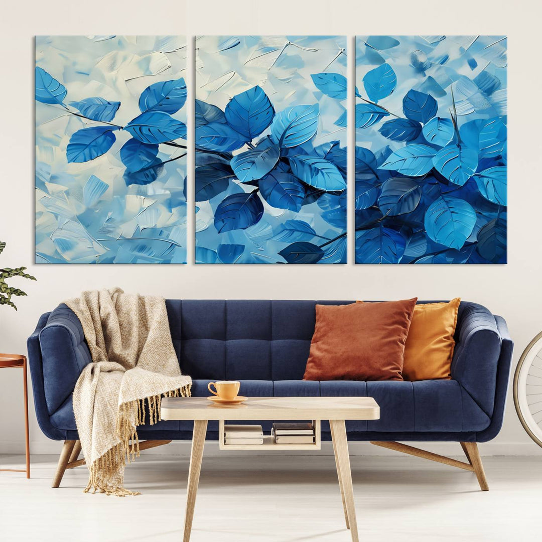 The contemporary living room is highlighted by the Abstract Blue Leaf Wall Art Canvas Print on the wall. The hand-assembled framed art enhances the room's vibrant decor, crafting a gallery-worthy ambience.