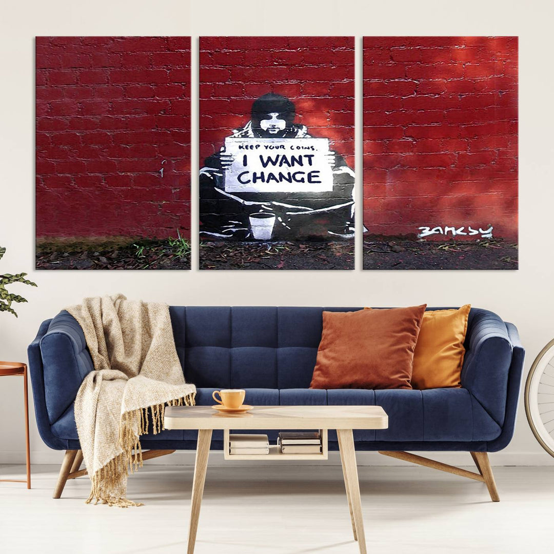 The living room showcases a triptych of stencil artwork on museum-quality canvas, featuring the Banksy I Want Change Graffiti Abstract Wall Art Canvas Print. This captivating piece depicts a person holding a sign that says "I want change" and is finished with a UV-protective coating to ensure long-lasting beauty.