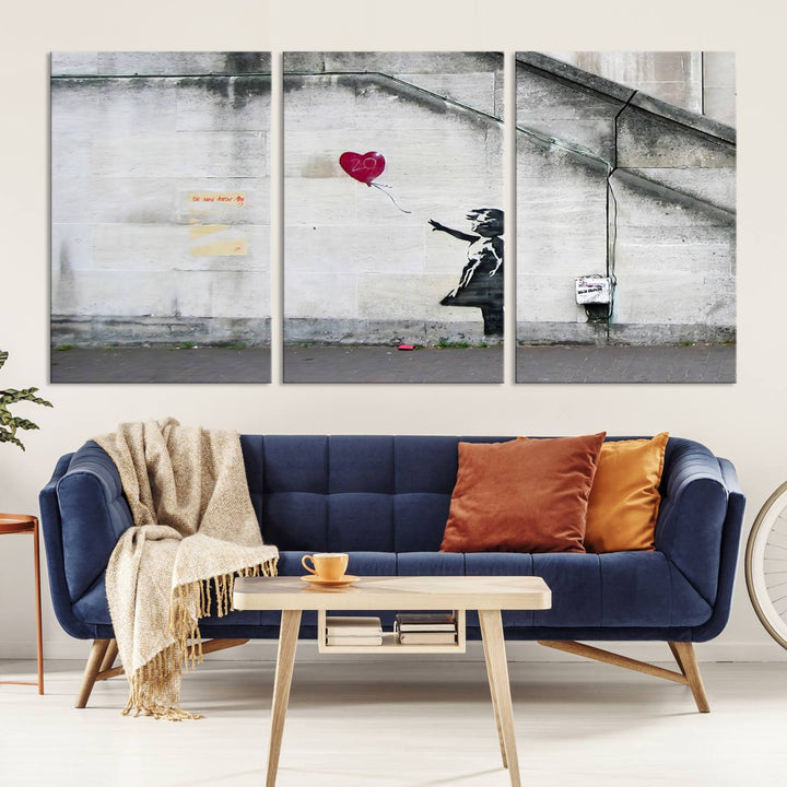 The "Girl with a Balloon Banksy Street Graffiti Art Canvas Print" is a gallery-quality wall art piece that features an image of a girl releasing a heart-shaped balloon. Handmade in the USA, this canvas artwork brings charm and emotion to any room.