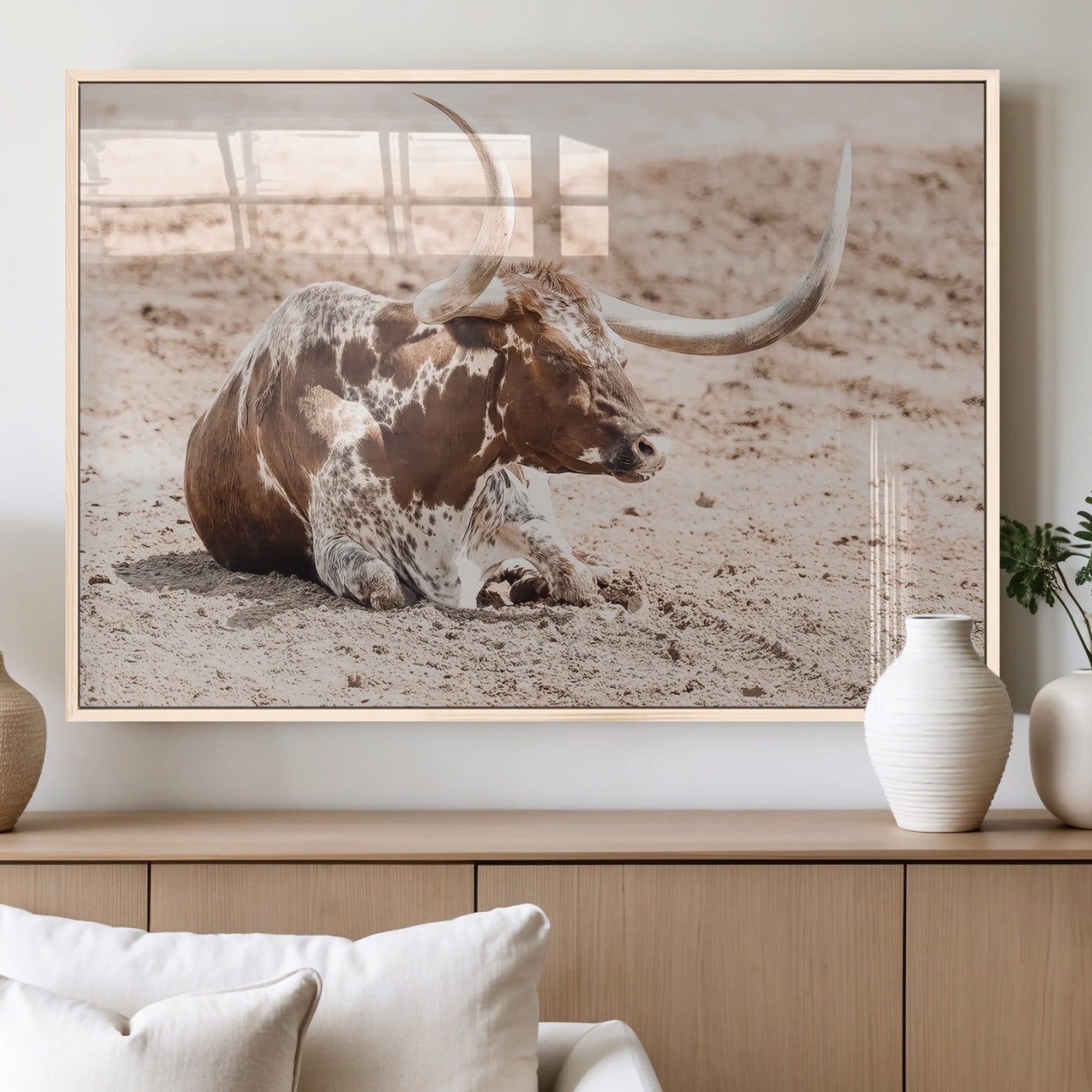 Texas Longhorn bull resting on dusty ground with warm tones, ideal for rustic western or farmhouse-themed wall decor.