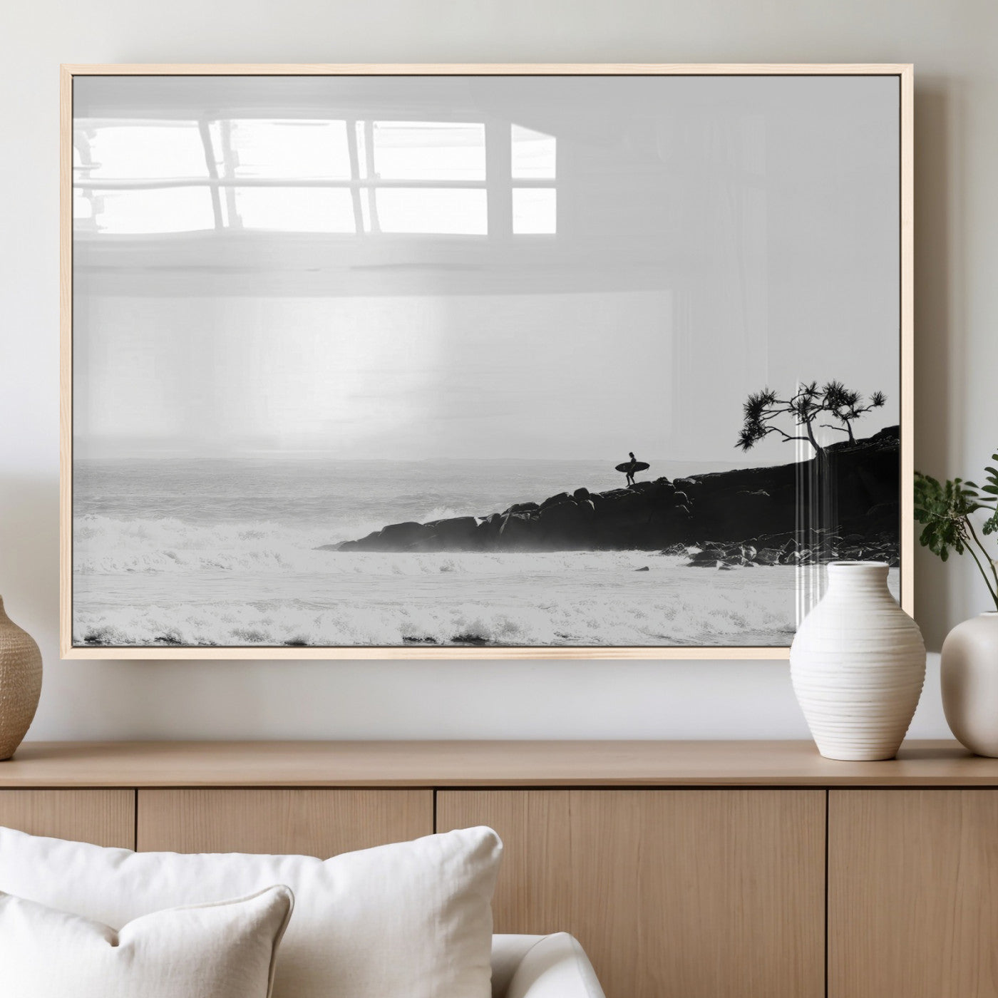Black and white photo of a surfer standing on rocky cliffs, gazing at the waves, embodying the spirit of adventure and solitude.