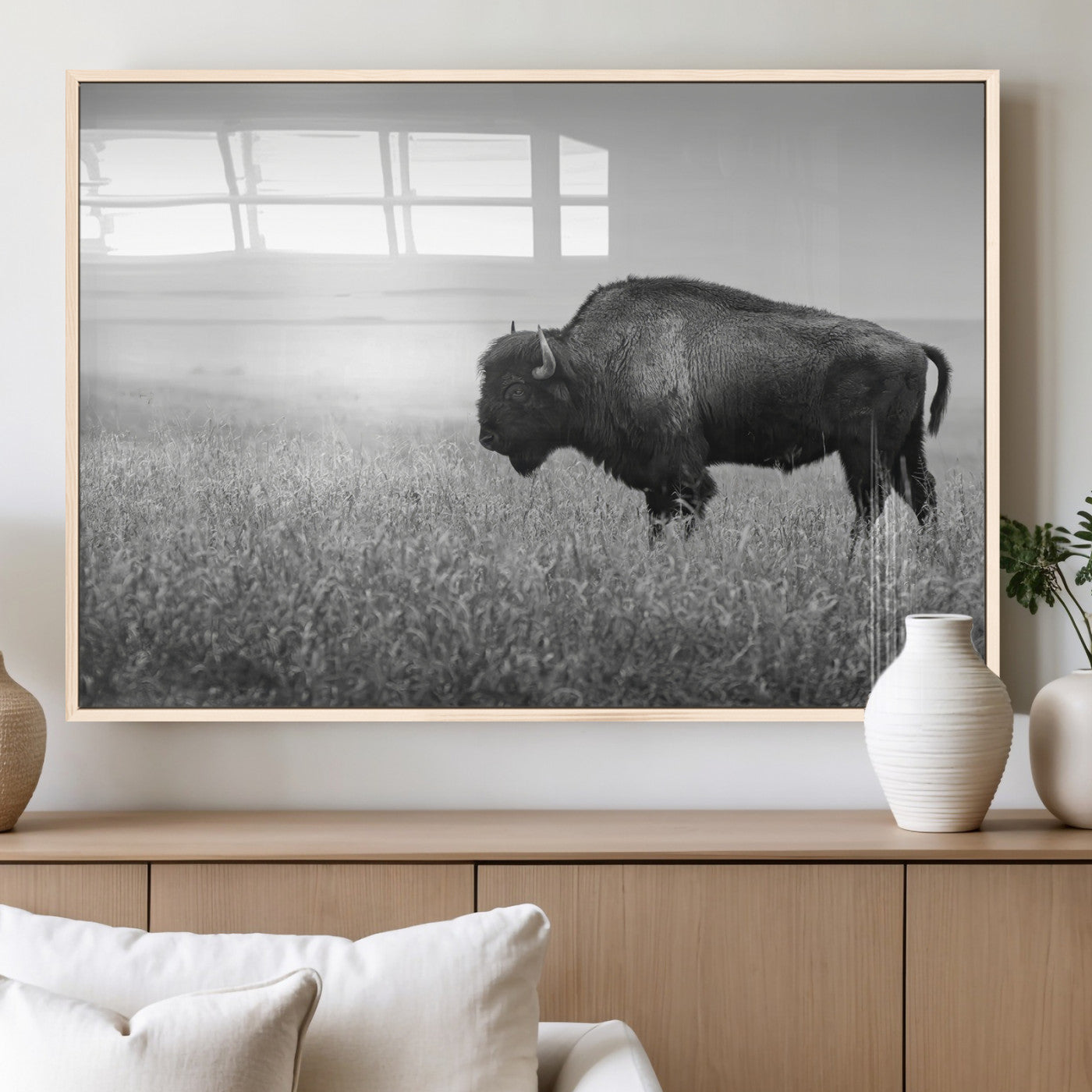 A black and white photograph of a majestic bison standing in a vast grassy prairie, evoking a sense of wilderness and strength.