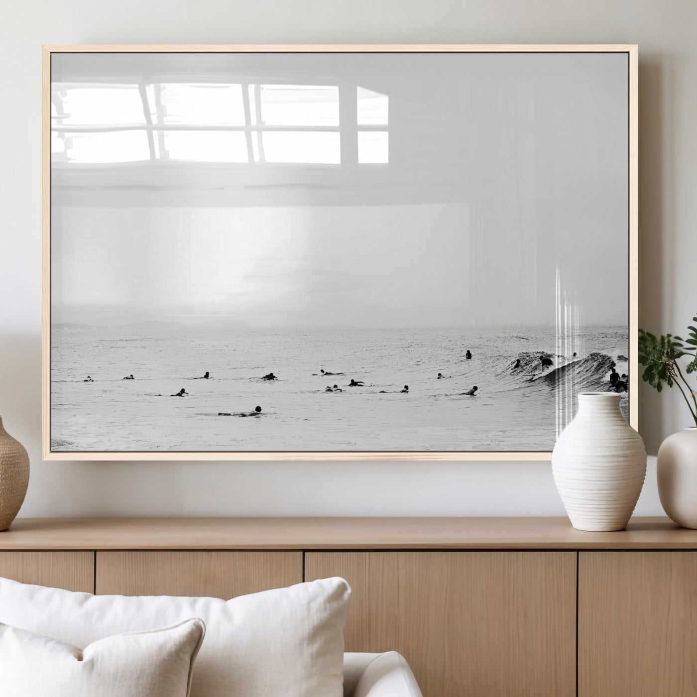 A group of surfers floating in the ocean, waiting for waves under a vast, moody sky, captured in black and white.