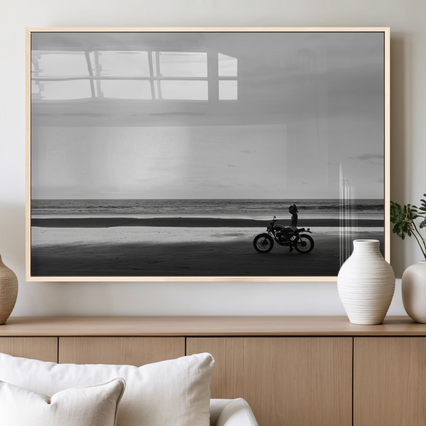 A motorcyclist on a vast beach, gazing at the ocean, capturing a moody and tranquil coastal adventure in black and white.