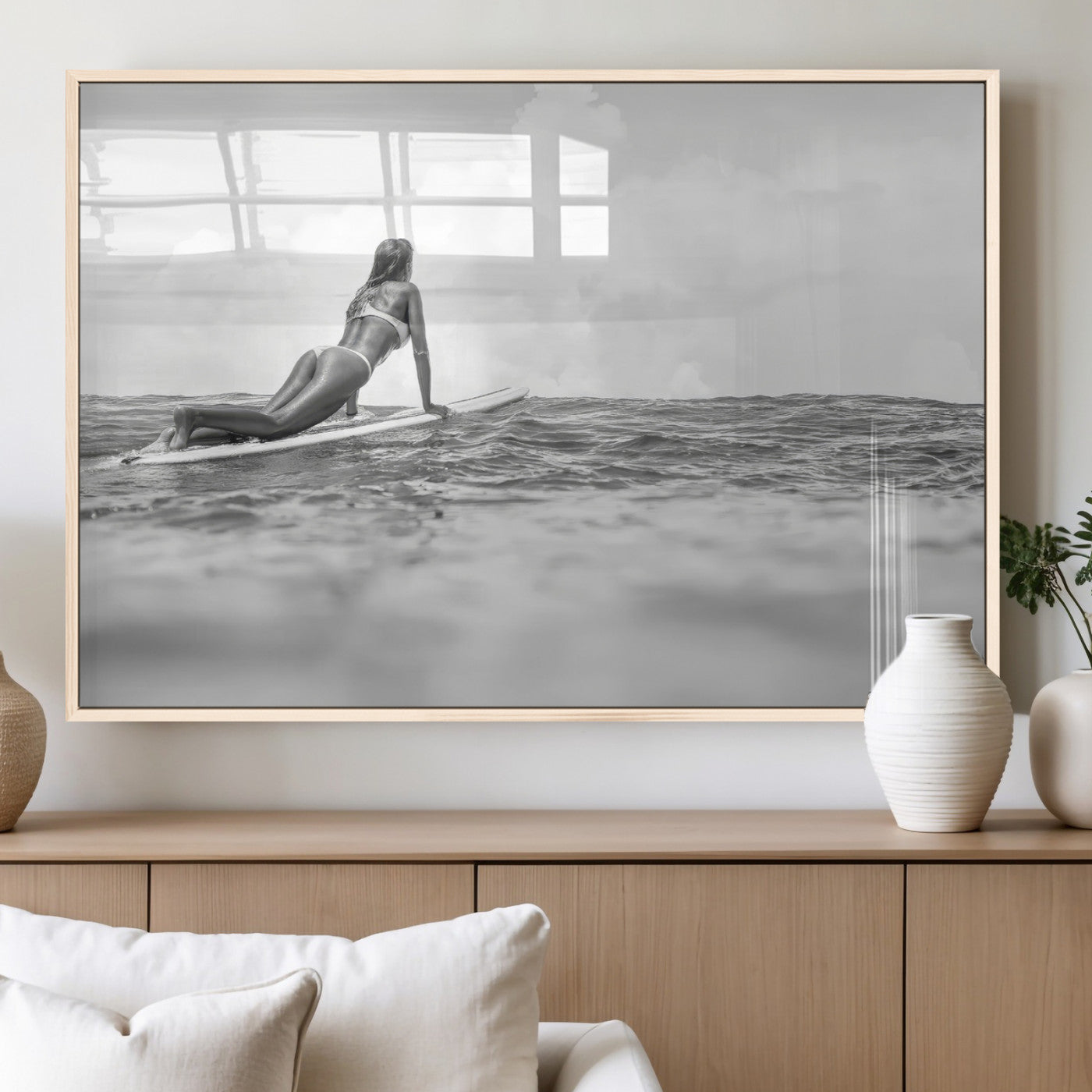 A black and white ocean scene featuring a surfer girl waiting on her board, gazing at the horizon, capturing a tranquil and adventurous coastal moment.