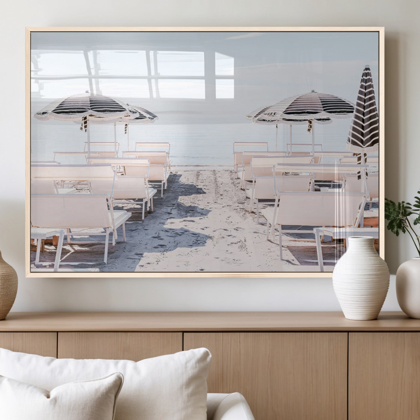 A serene minimalist beach scene featuring striped umbrellas, soft pastel sand, and an elegant lounge setup, creating a tranquil and stylish coastal retreat.