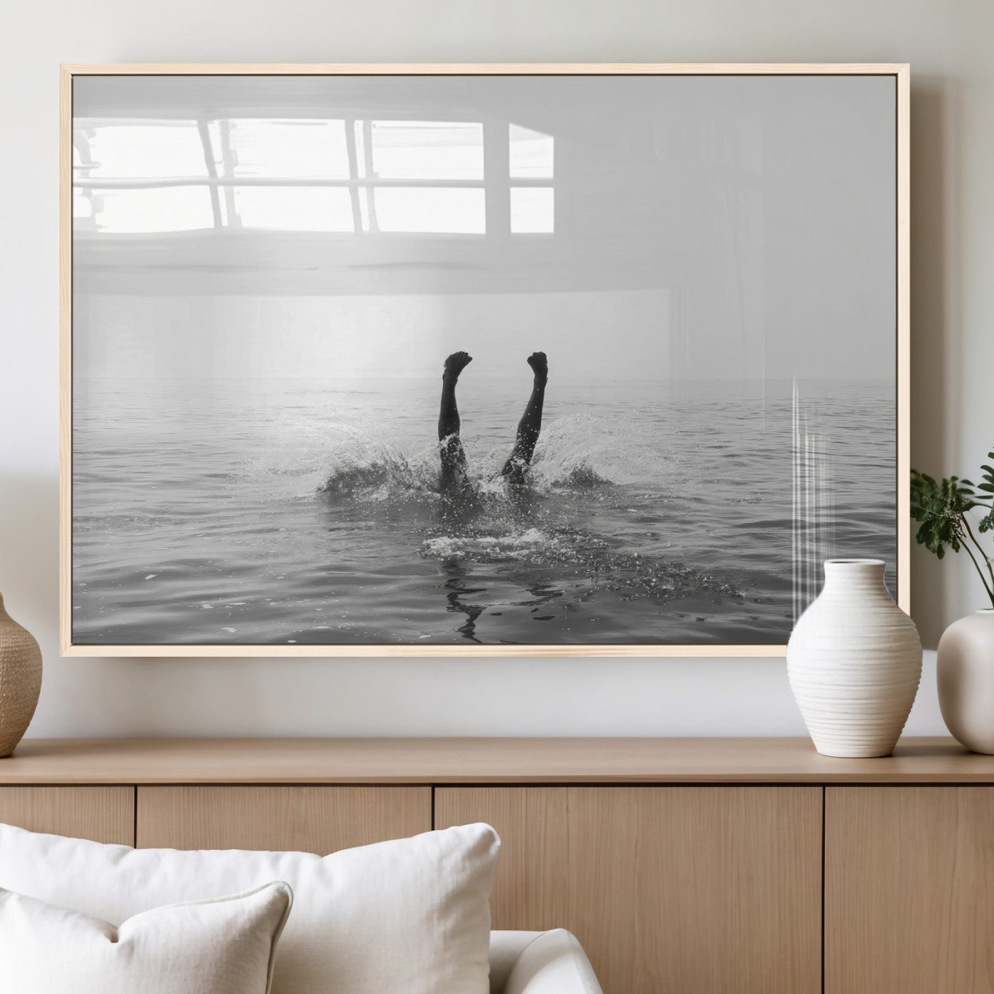 A black and white minimalist water scene capturing a playful splash as a swimmer dives upside down, creating a carefree and artistic aquatic aesthetic.
