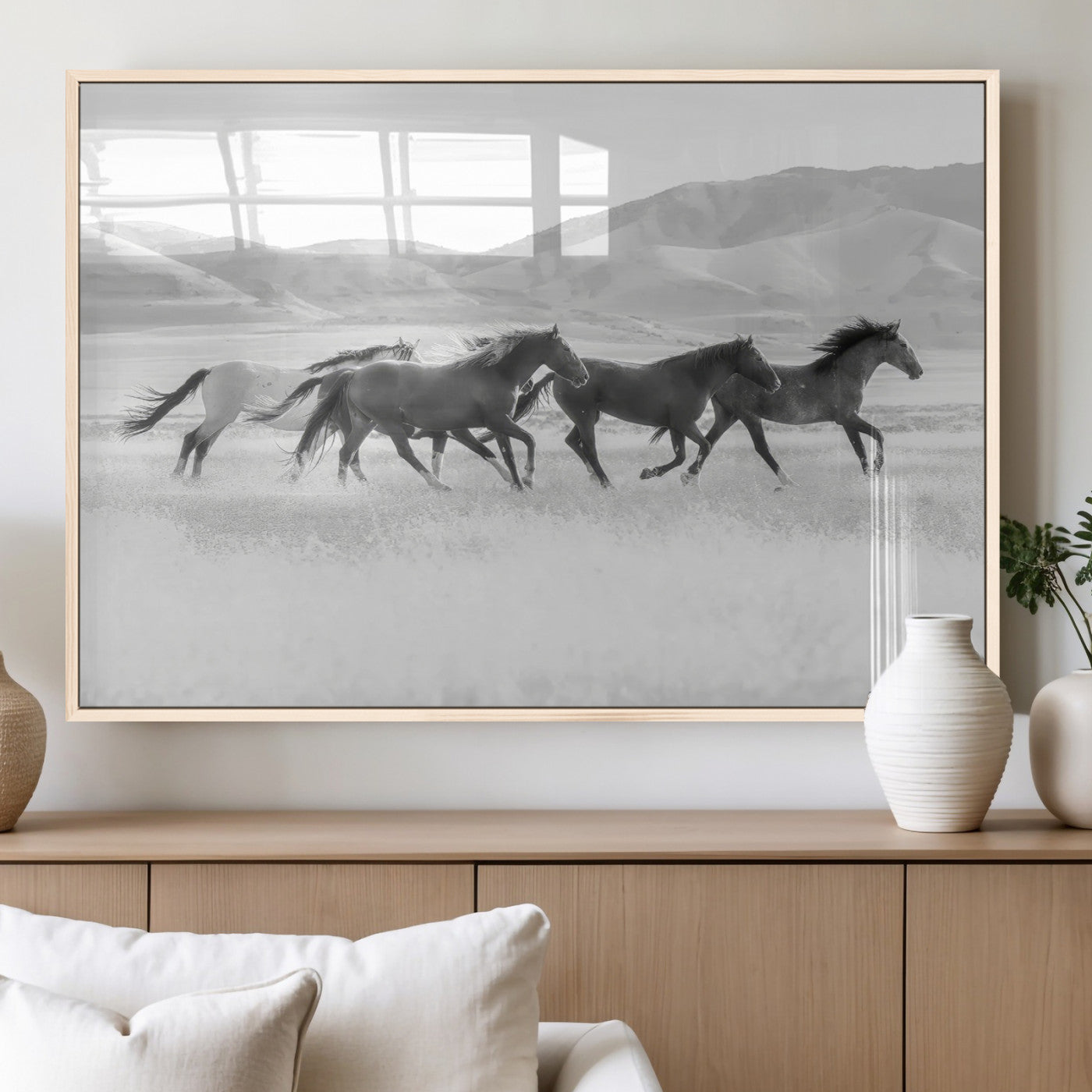 A black and white image of wild horses running freely across an open grassland, capturing the power and beauty of untamed nature in a rustic western setting.