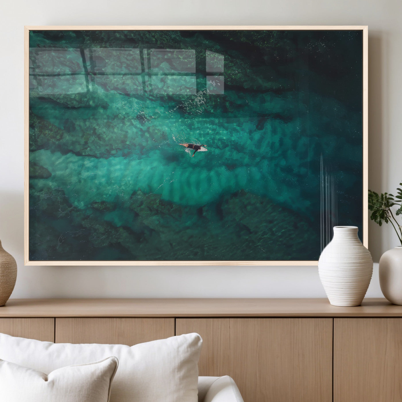 An aerial view of a solo surfer paddling through crystal-clear turquoise waters over a sunlit reef, capturing the beauty and serenity of open water surfing.