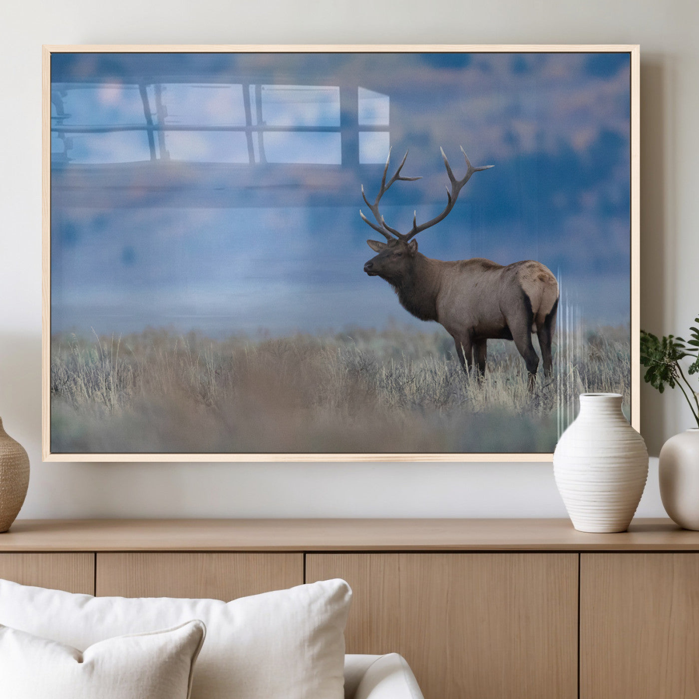 Elk with large antlers standing in open field, mountains blurred in background, perfect for rustic cabin or lodge-style decor.