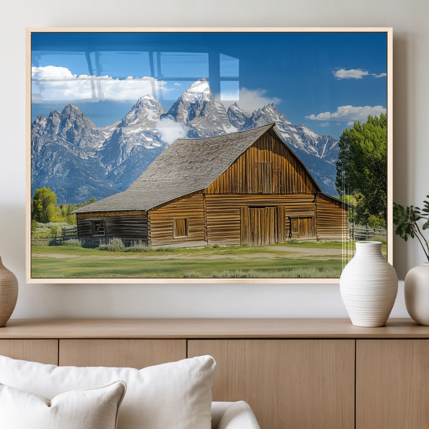 A rustic wooden barn sits in front of towering mountain peaks under a clear blue sky, perfect for farmhouse or cabin style interiors.
