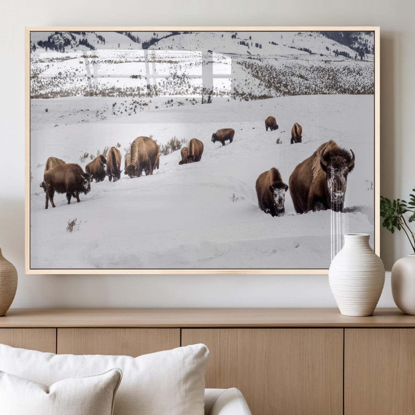 A herd of bison walking through deep snow in a mountain valley, perfect for rustic, cabin or western-themed wall decor.