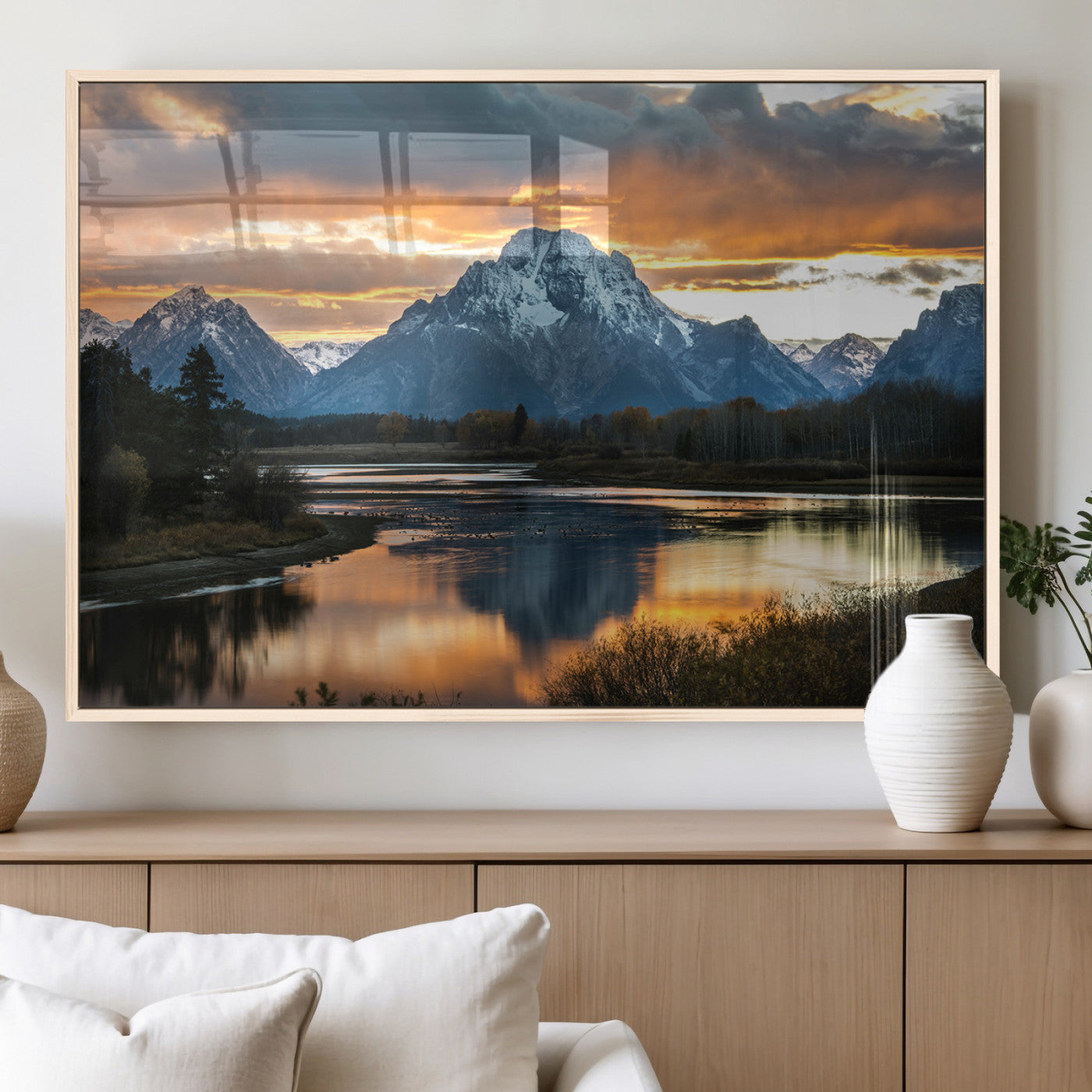 Snow-capped mountains reflecting in a calm lake at sunset, with a dramatic golden sky creating a breathtaking wilderness scene.