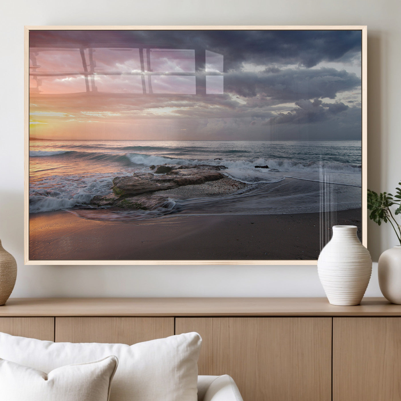 Dramatic sunset over a rocky shoreline with ocean waves gently reaching the sandy beach, creating a serene and coastal atmosphere.