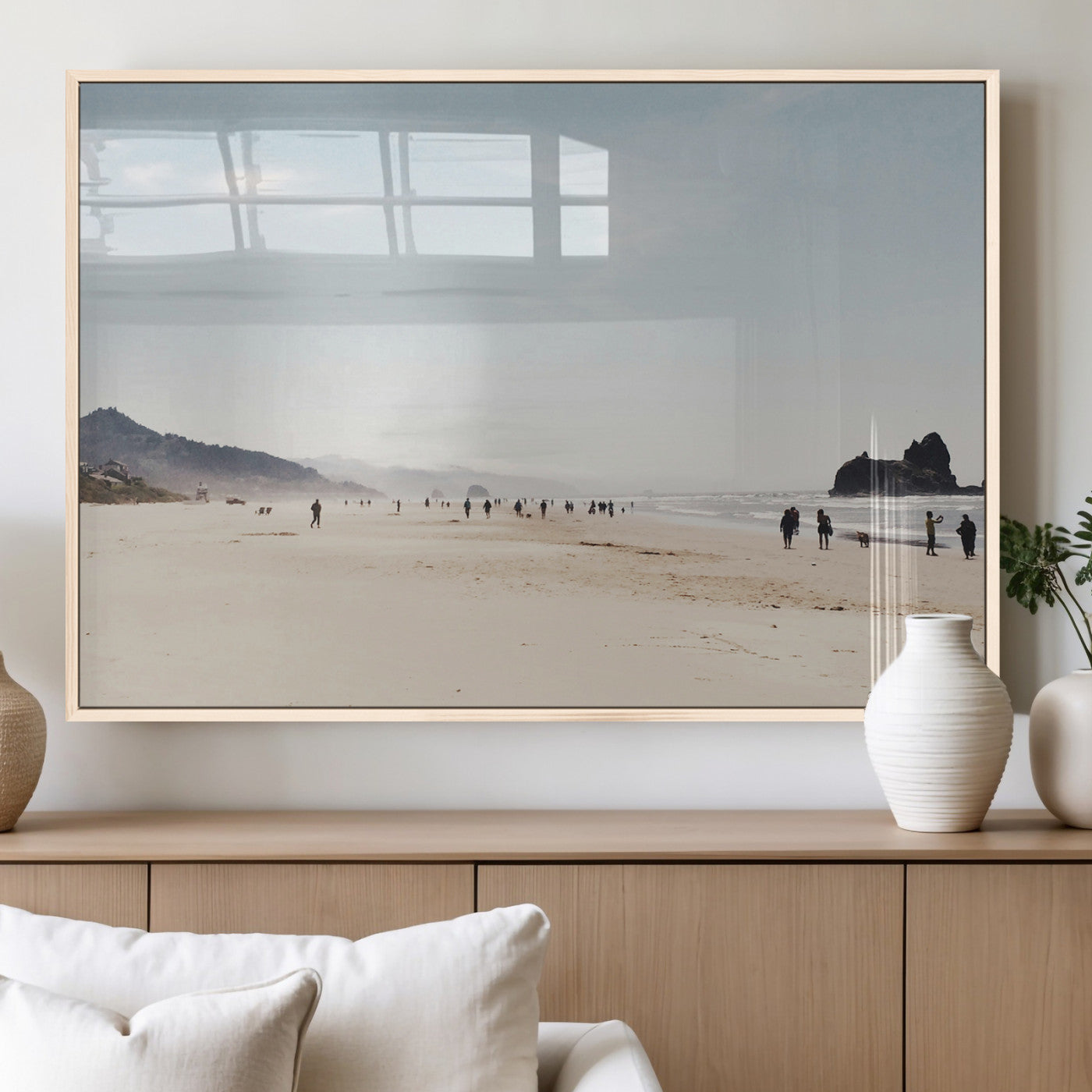 A serene beach with soft sand, misty mountains, and scattered people walking along the shoreline, creating a peaceful coastal landscape.