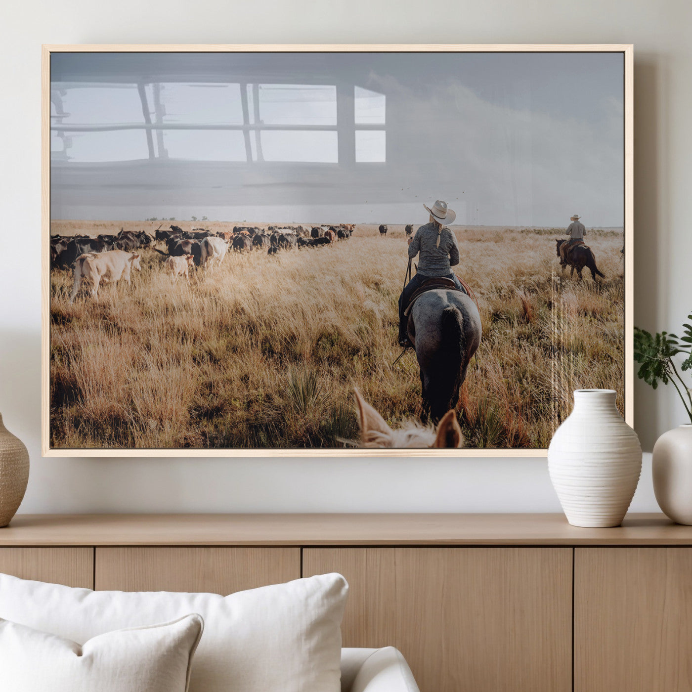 A cowboy and cowgirl on horseback herding cattle through golden grasslands, capturing a rustic and authentic Western ranch lifestyle.