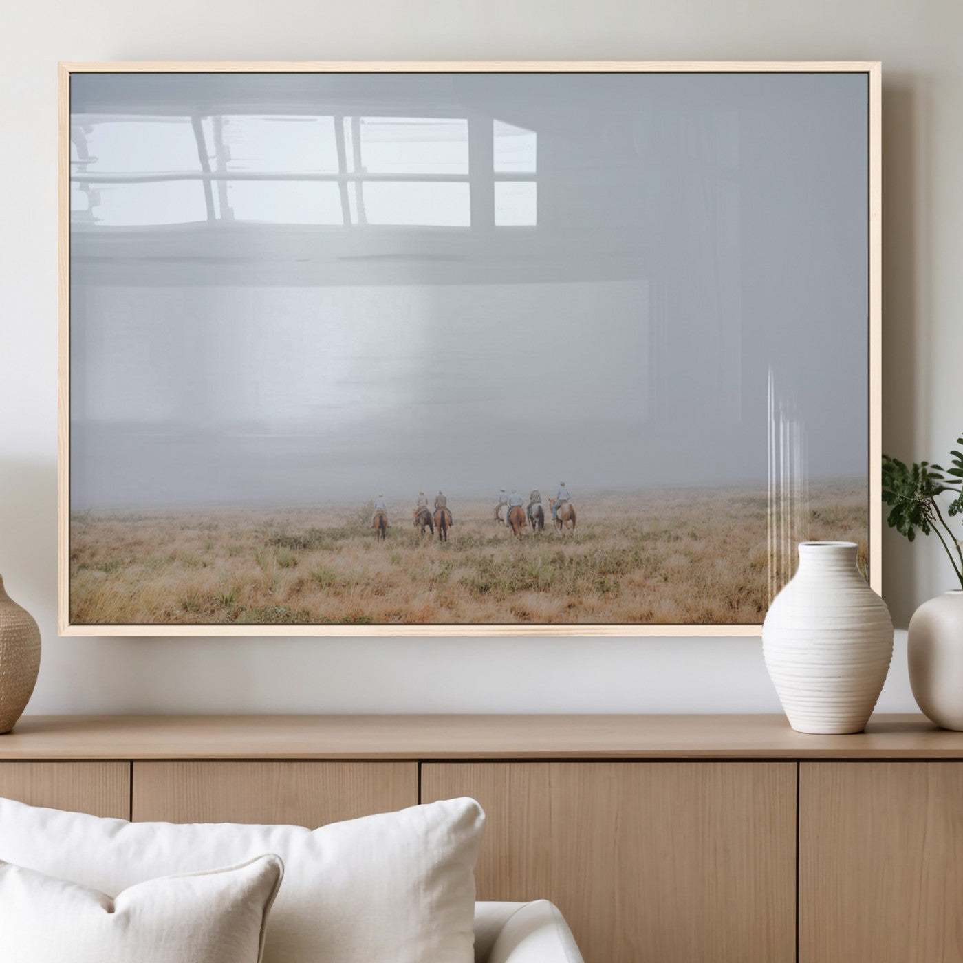 A group of horseback riders moving through a fog-shrouded field, evoking a calm Western scene with golden grasses and soft horizons.