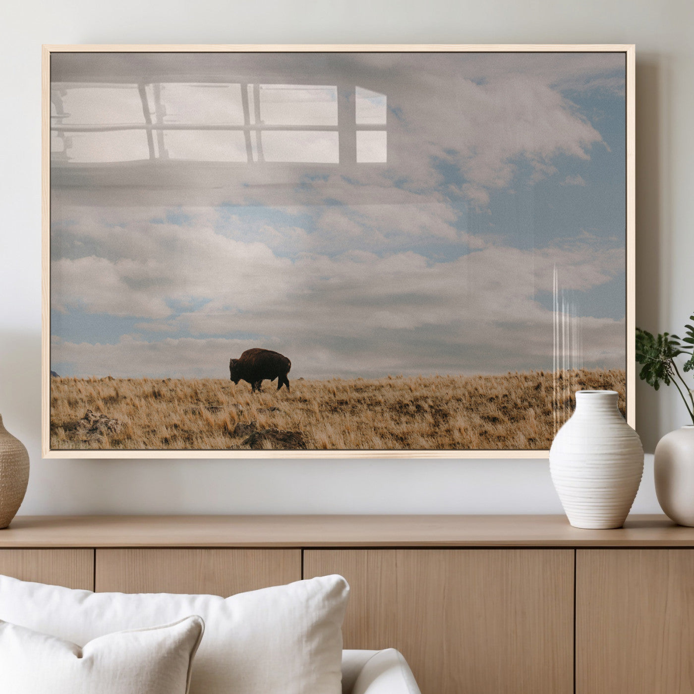 A solitary bison walking across a golden prairie under a vast, cloud-filled sky, evoking a peaceful, rustic western landscape for home decor.