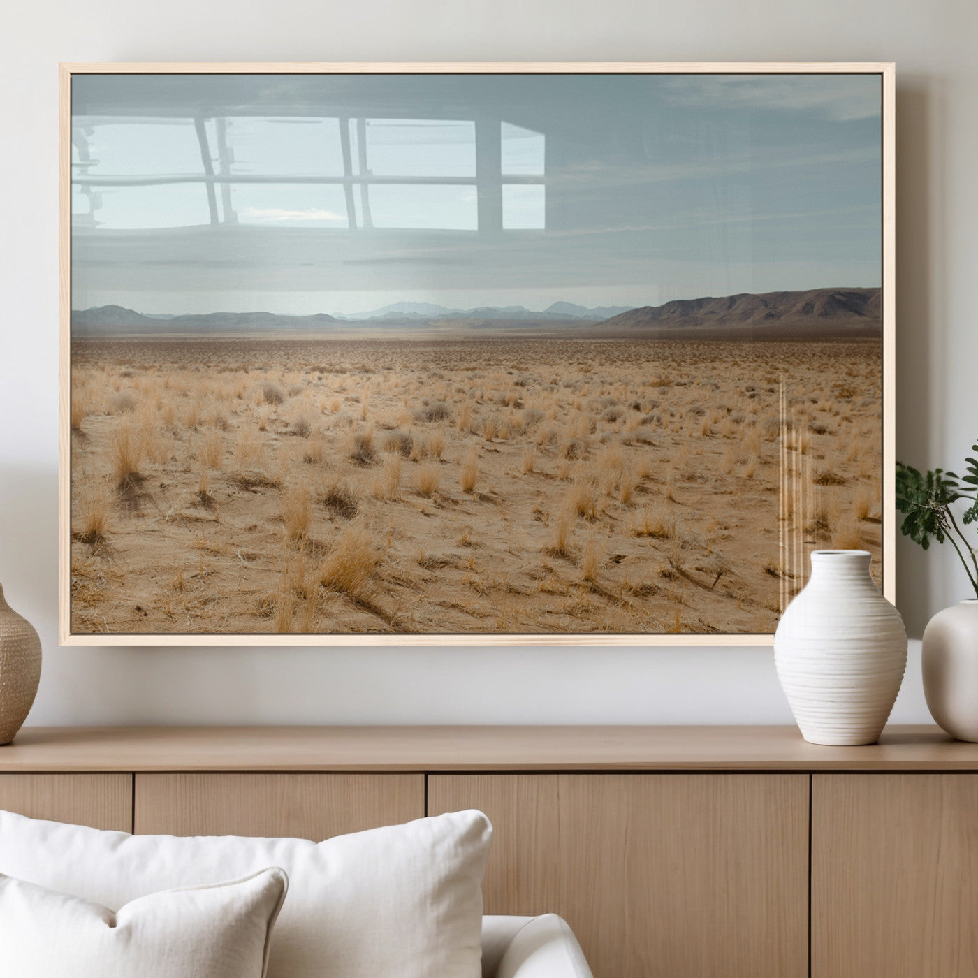 Expansive desert landscape with scattered dry grass and distant mountain range under a pale blue sky – Wall Art Canvas Print.